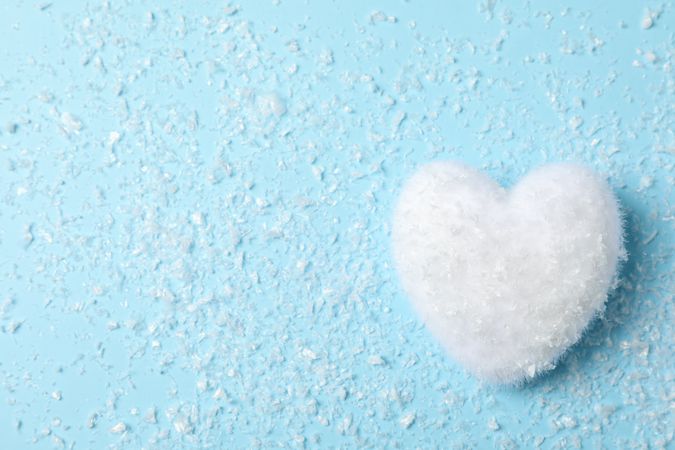 Snow and decorative heart on blue background, space for text