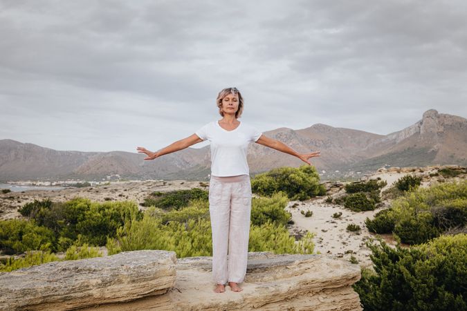 Barefoot woman meditating on stone