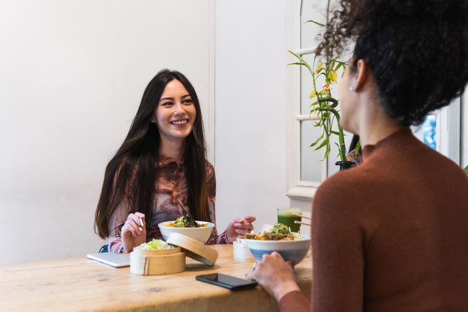Delighted friendly multiethnic women eating in restaurant