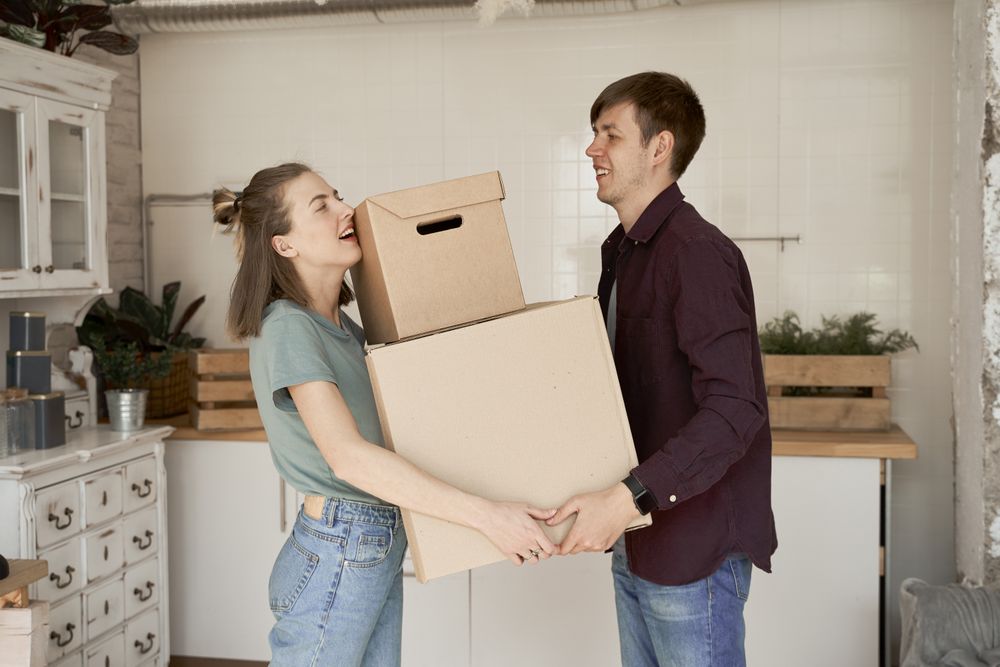 Young couple carrying big carton boxes in house