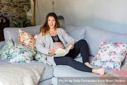 Pregnant woman relaxing on sofa with book 48w2k5