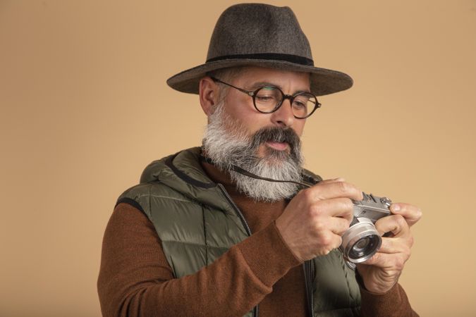 Bearded photographer with hat looking at vintage camera
