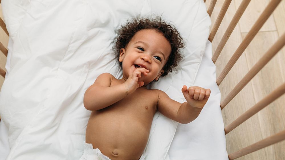 Happy baby boy lying in his crib