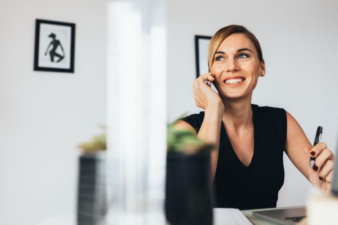 Woman sitting at her desk in office talking over mobile phone
