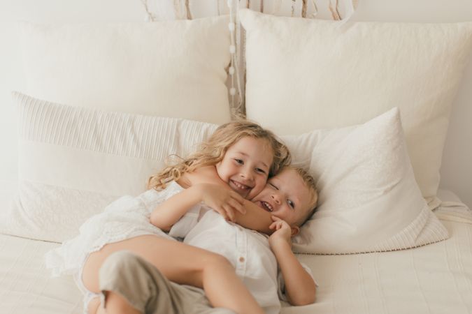 Sister embracing little brother at home