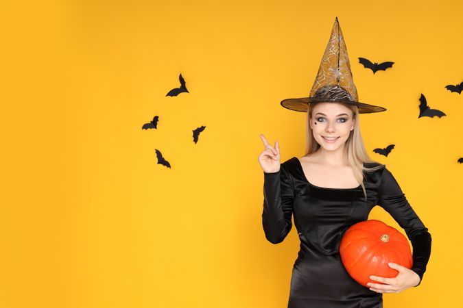 Concept of Halloween, young woman on yellow background