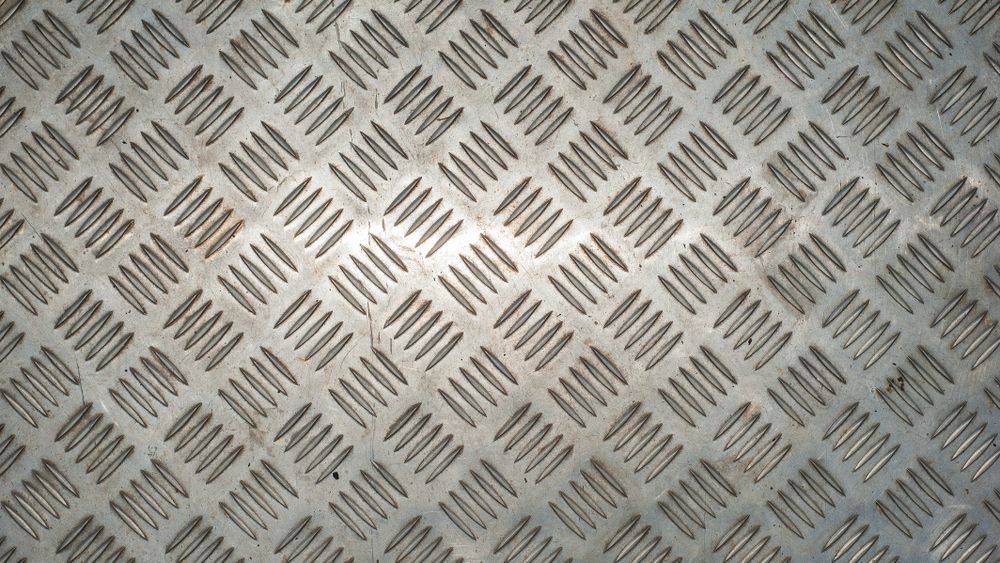 Silver metal floor plate with diamond pattern and polished steel texture