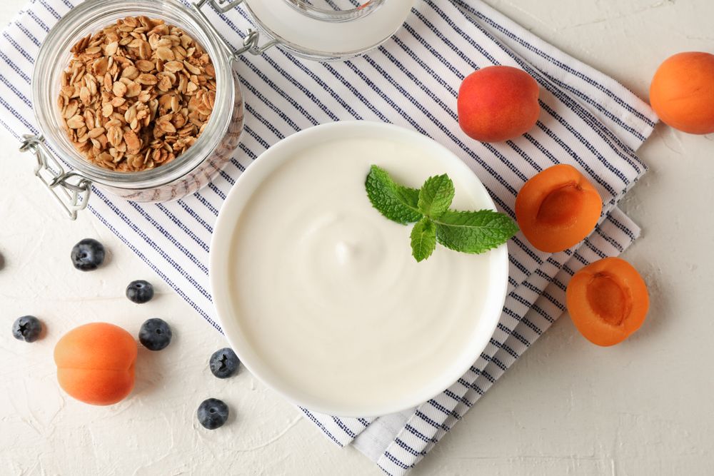 Composition with granola, yogurt and fresh fruits on cement background