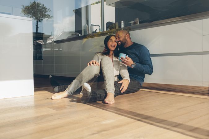 Happy young man and woman sitting on kitchen floor