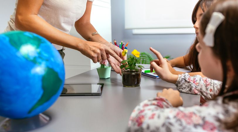 Teacher and young students pointing to pansy plant in ecology classroom