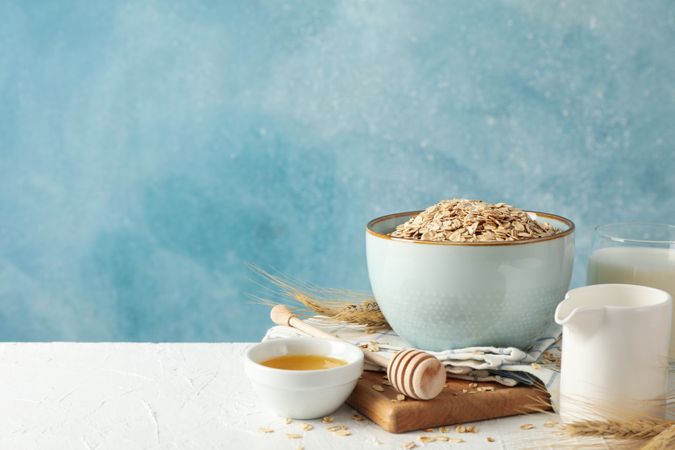 Composition with oatmeal flakes and milk on table. Cooking breakfast