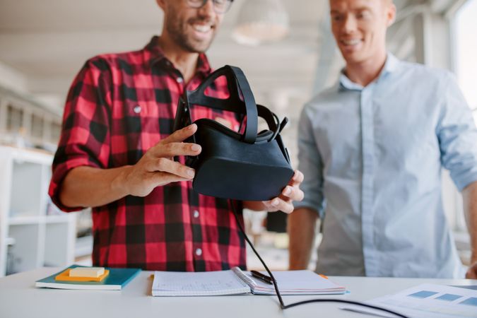 Shot of two men using virtual reality goggles in office