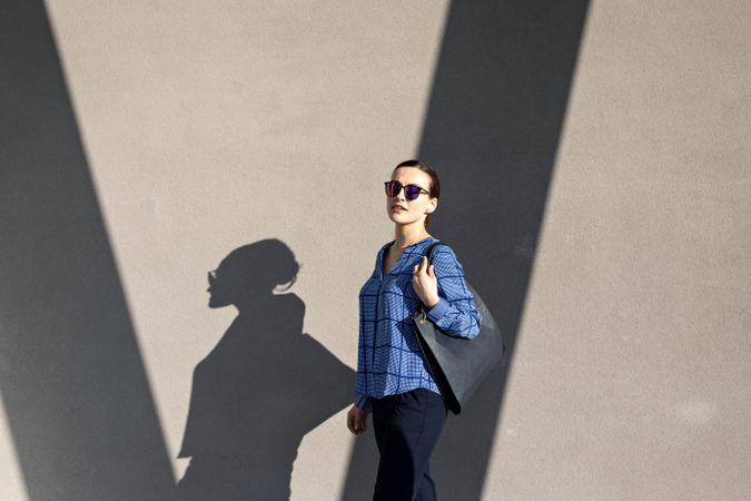 Smiling businesswoman standing near gray wall