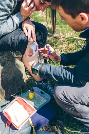 Man healing knee to woman who has been injured trekking