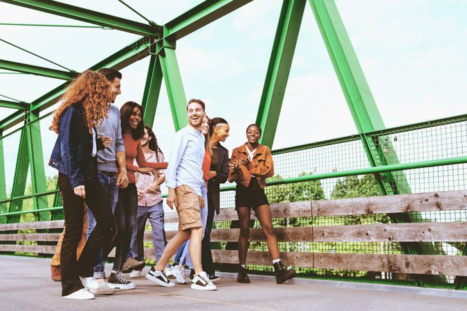 Multiracial people walking together crossing a bridge on a beautiful day