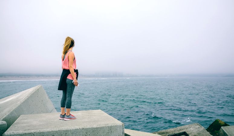 Young woman on concrete block watching the sea