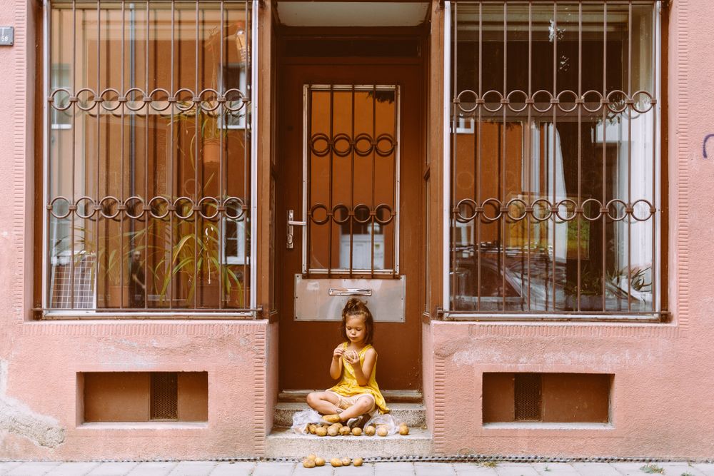 Preschool child sitting with potatoes in doorway