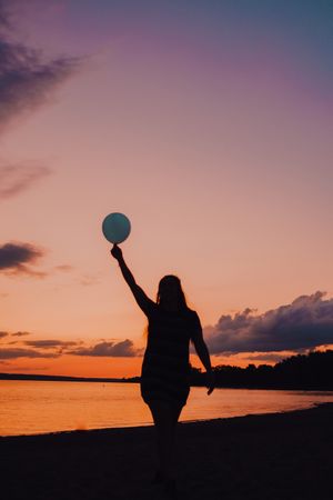 Unrecognizable female walking along beach during sunset