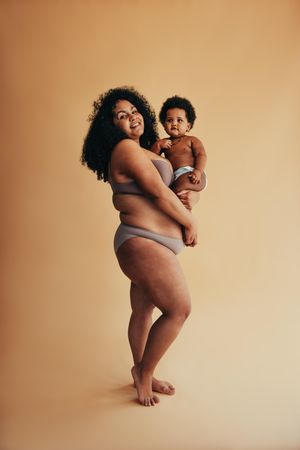 Happy woman celebrating her mom body with her baby