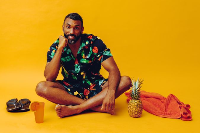 Black male sitting in yellow room with towel and tropical drink