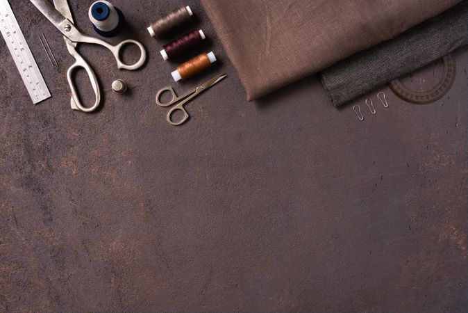 Seweing kit with thread and scissors on brown background