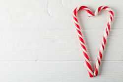 Sweet candy canes on wooden background, space for text