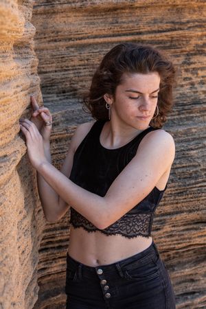 Young female leaning on sandstone rock