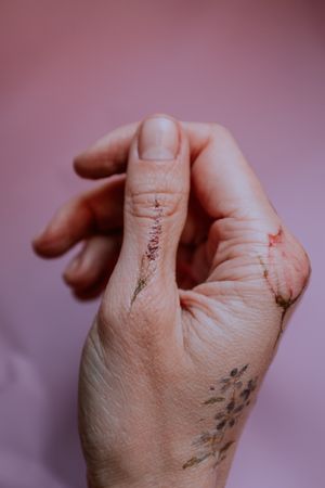 Floral tattoos on right hand against pink wall