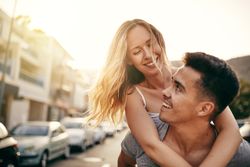 Woman smiling while on her boyfriends back