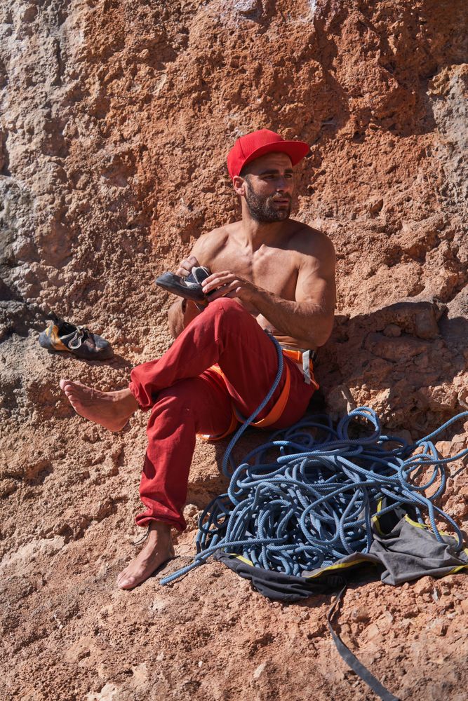 Man with climbing shoes near rock
