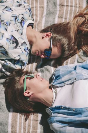 Women friends with sunglasses looking each other lying