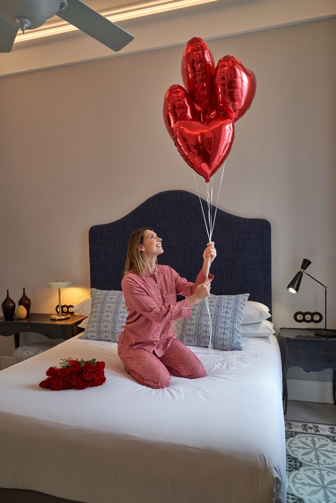 Woman with red heart balloons and bouquet of roses