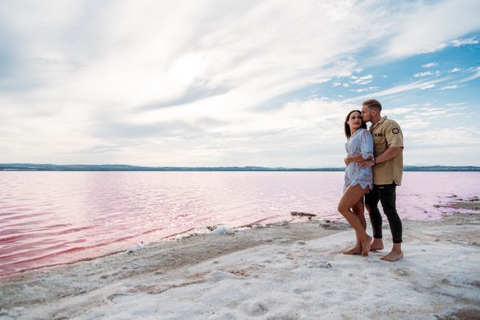 adorable couple standing on an amazing beach with pink water