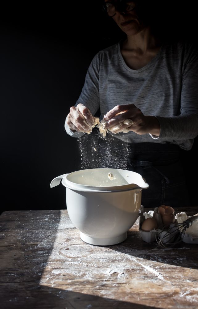 Person cracking egg in bowl on table