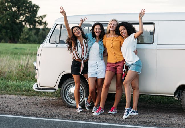 Multi-ethnic group of friends post outside a van