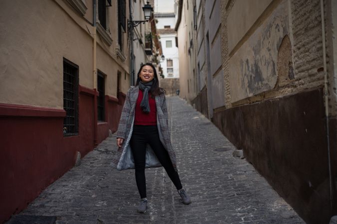 Joyful Asian resting female hiking on old rocked narrow street