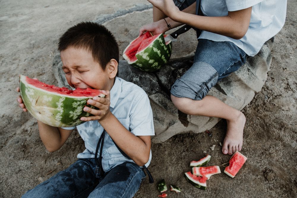 Children in uniform eating sliced watermelon