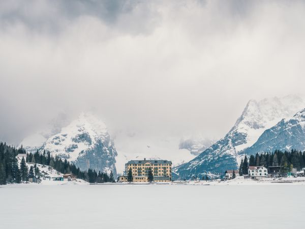 Beautiful building in snow surrounded by forest and mountains