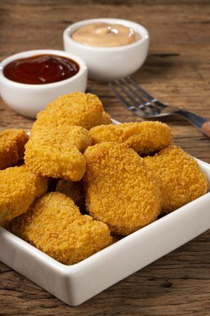 Fried chicken nuggets with ketchp and rose sauce.