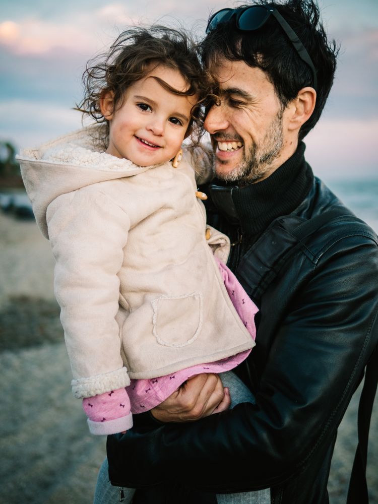 father holding little daughter at the beach