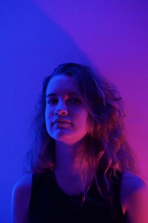 Portrait of blonde teenage girl in purple lit studio
