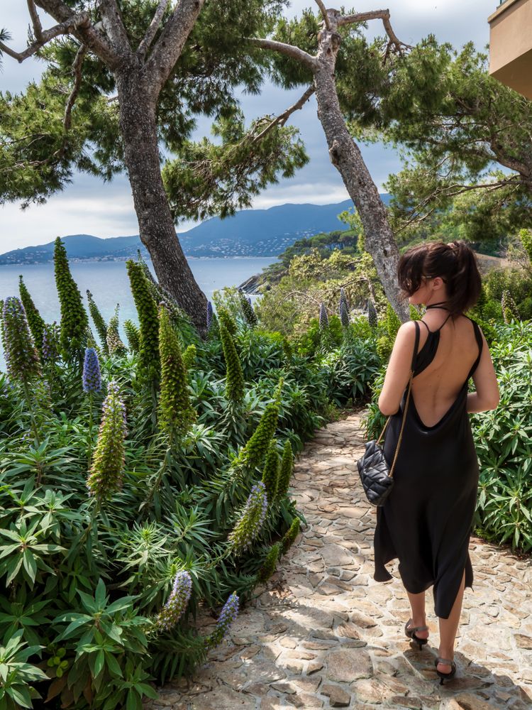 Young woman in a chic dress elegantly poses near the pool at a luxurious villa