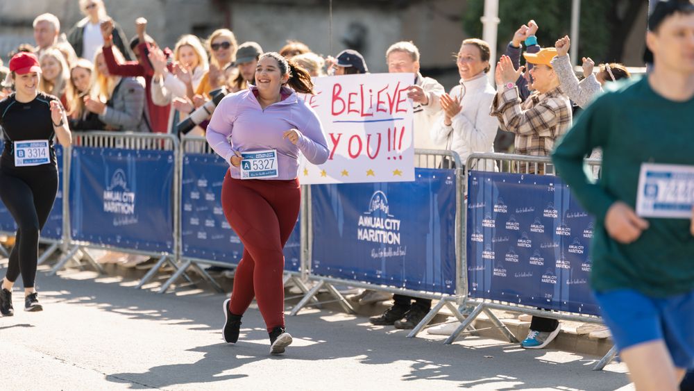 Portrait of a Smiling Plus Size Female Runner Crossing the Finish Line and Demonstrating her Willpower.