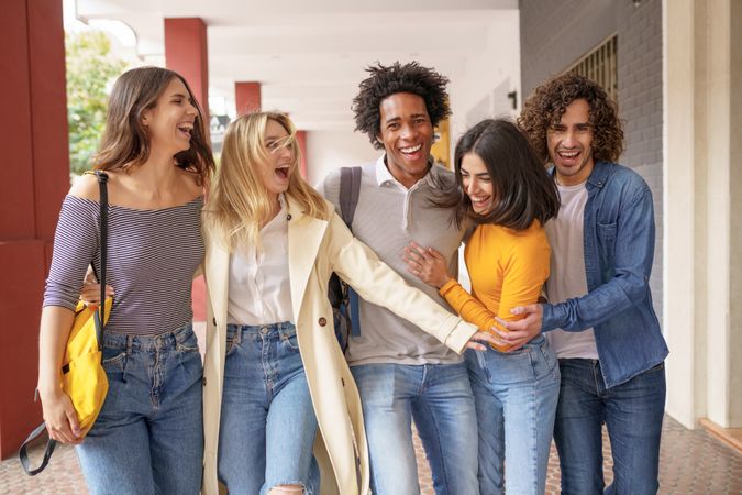 Multi-ethnic group of friends walking down the street outside and goofing around