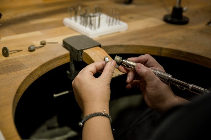 unrecognizable woman grinding ring in jewelry atelier