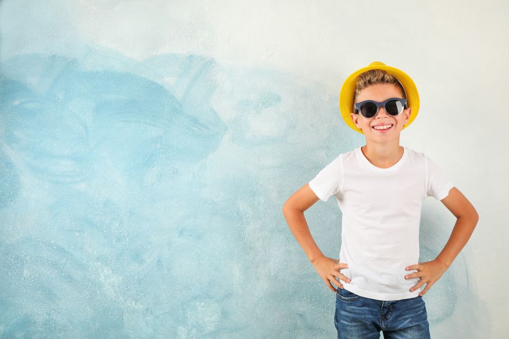 Boy with sunglasses and hat against color background, space for text