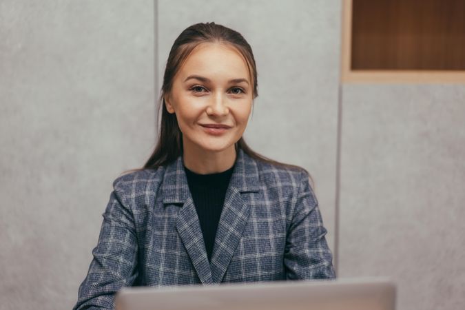 Smiling female looking up from her laptop at work