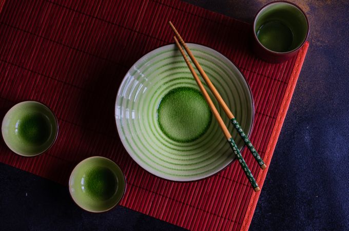Green bowl with chopsticks on red table setting