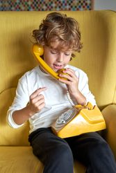 Boy talking on old fashioned telephone in room