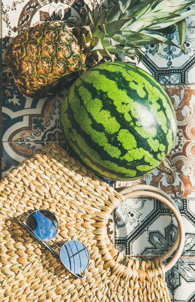Thatched bag on pattered tiles with sunglasses, watermelon vertical composition
